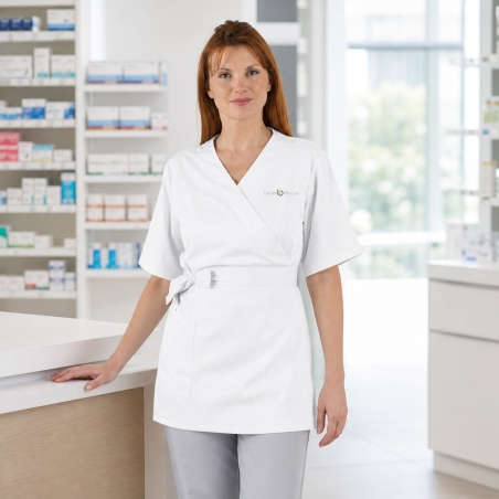 Blouse cache-cœur blanche portée en pharmacie — vue de face, logo brodé