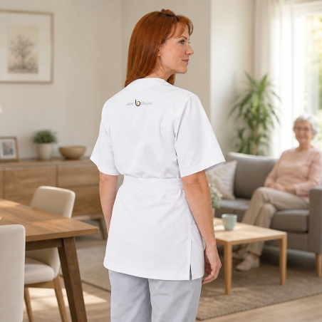 Blouse cache-cœur blanche portée en aide à domicile — vue de dos, logo brodé