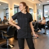 Coiffeuse portant la blouse Julia noire à col rond dans un salon de coiffure